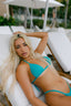 Woman in a turquoise bikini lying on a white lounge chair