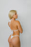 Woman wearing a white bikini against a plain background